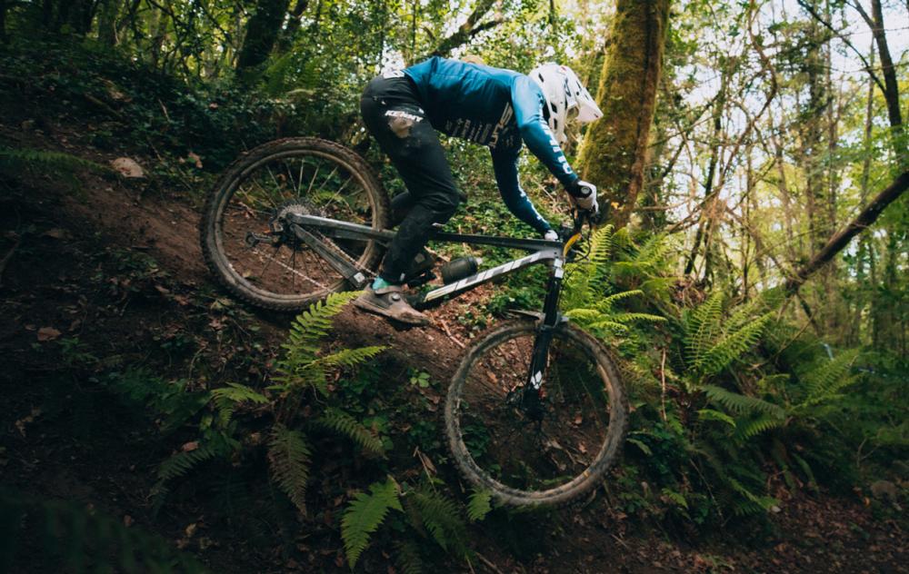 Mountainbiker mit Zefal Sense Pro 50 Trinkflasche schwarz/grau am Rad auf steilem Waldtrail.