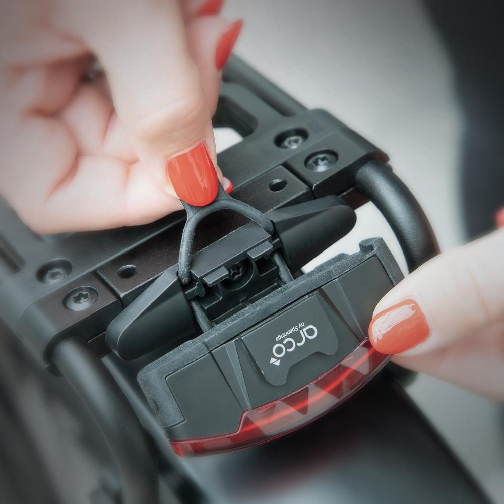 Person befestigt SKS INFINITY UNIVERSAL LED-Rücklicht (StVZO, USB-C) am Fahrrad-Gepäckträger.