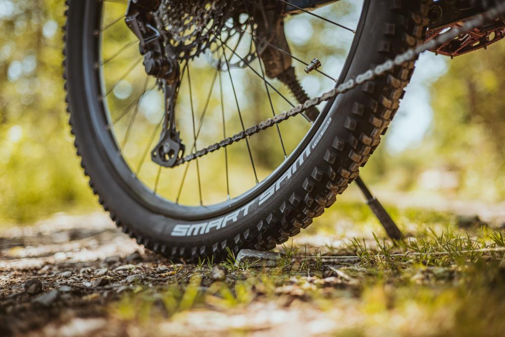 Schwalbe Smart Sam Performance 29 Zoll Drahtreifen am Hinterrad eines Mountainbikes auf einem unbefestigten Waldweg.