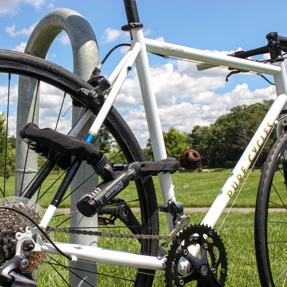 Kryptonite Keeper 790 Combo Kettenschloss (90cm, 7mm gehärteter Manganstahl, 4-stellige Kombi) sichert weißes Fahrrad.