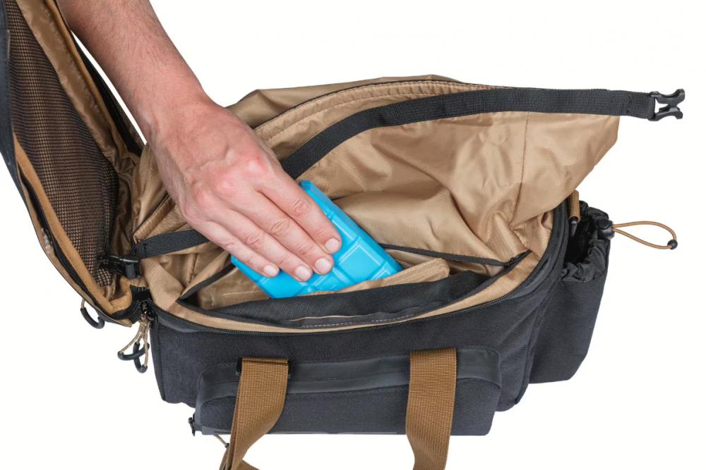 Hand steckt Kühlpack in wasserdichte Basil Miles XL Pro MIK 2.0 Gepäckträgertasche (36L, schwarz/grau) mit Innenfächern.