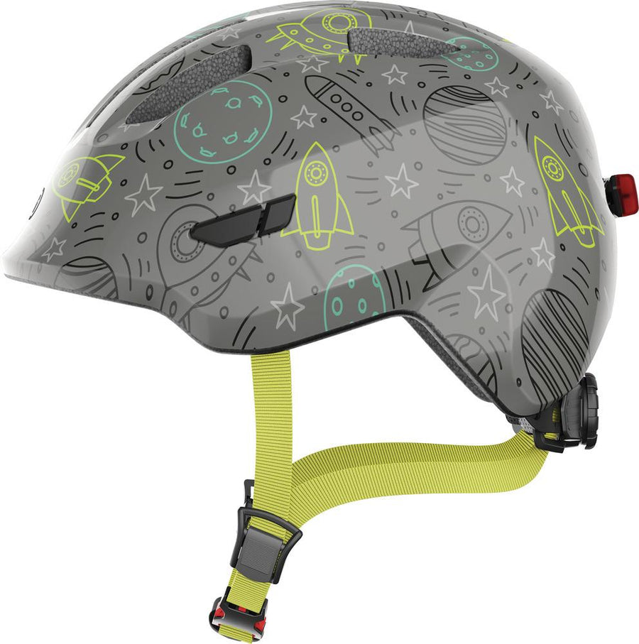Abus Kinderhelm Smiley 3.0 LED grey space mit Raketen und Sternen, Größe S 45-50cm, gelbe Riemen, Seitenansicht.