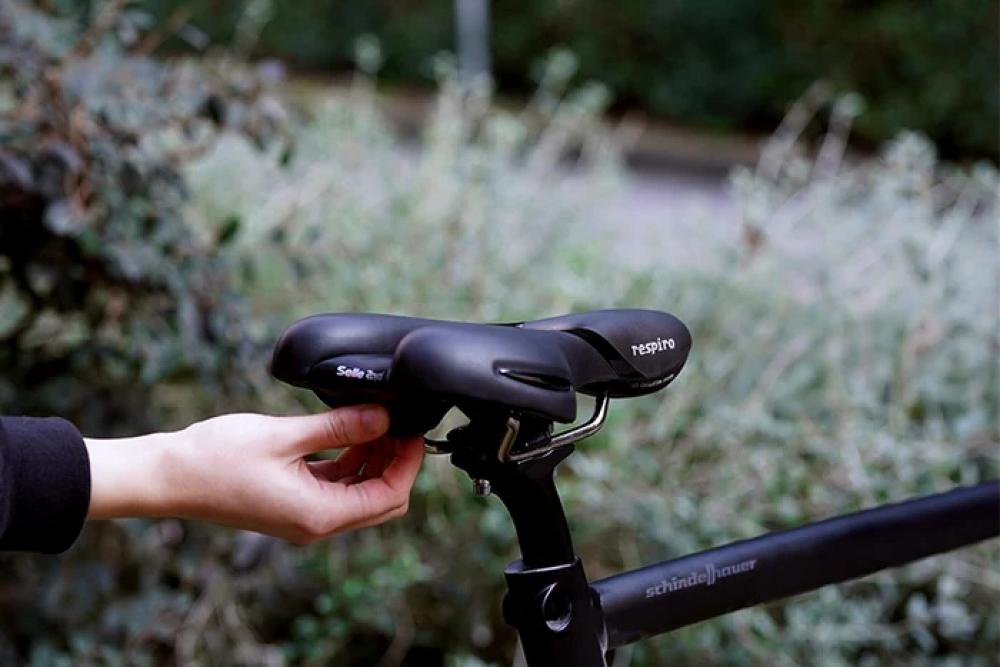 Eine Hand hält einen schwarzen Selle Royal Respiro Fahrradsattel, der kühlen Komfort für sportliche Fahrten bietet.