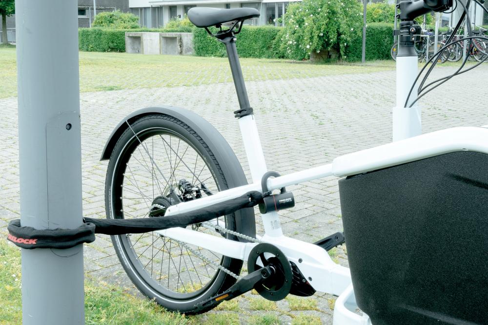 Trelock Kettenschloss LC 680 schwarz sichert Lastenrad an einem Pfahl.