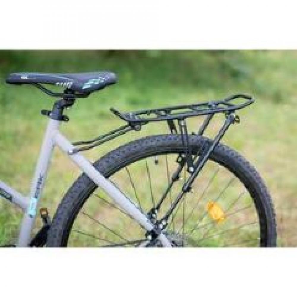 Schwarzer M-WAVE Gepäckträger ONE-4-ALL, verstellbar für 20-29 Zoll, montiert am Hinterrad eines Fahrrads.